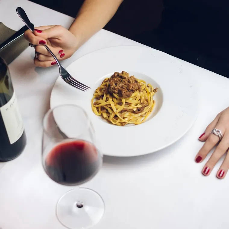 Tagliolini serviti con un calice di vino rosso